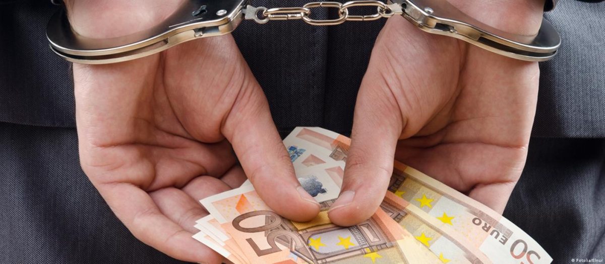 руки в наручниках, держащие евро